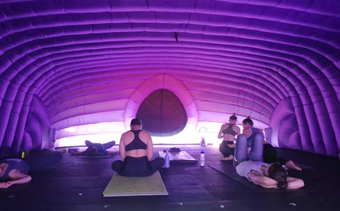 HotPod yoga class in session inside a dome with purple mood lighting